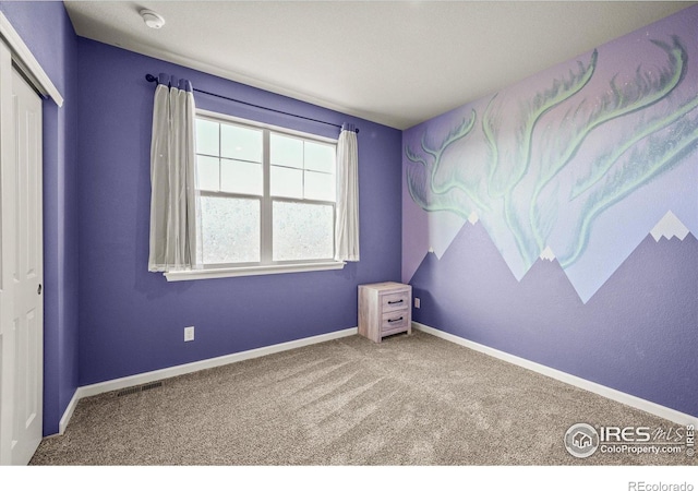carpeted empty room featuring a smoke detector and baseboards