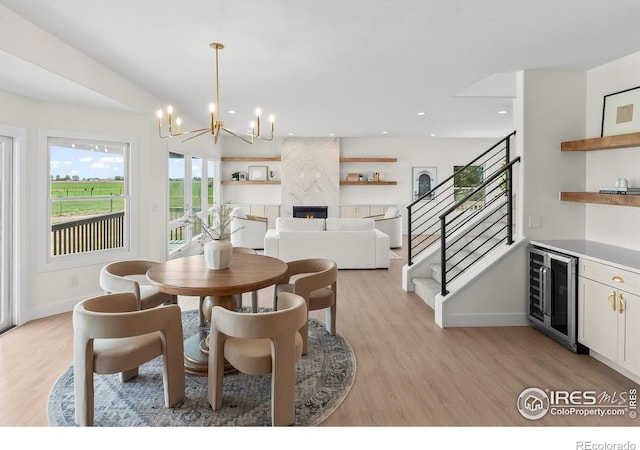 dining room with beverage cooler, stairs, light wood-type flooring, a chandelier, and recessed lighting