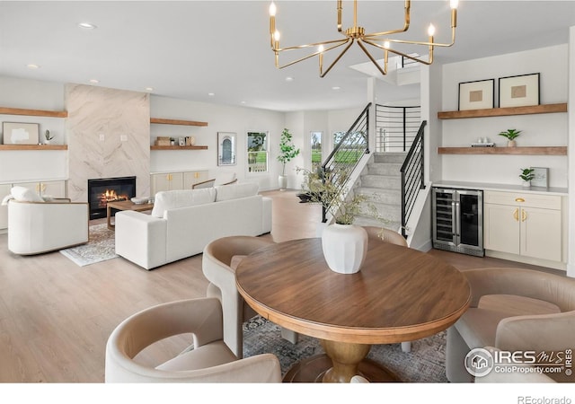 dining area with beverage cooler, light wood finished floors, a chandelier, recessed lighting, and stairs