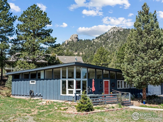 1411 Vail Ct, Estes Park, CO 80517 - view of front facade with board and batten siding, a sunroom, and a mountain view