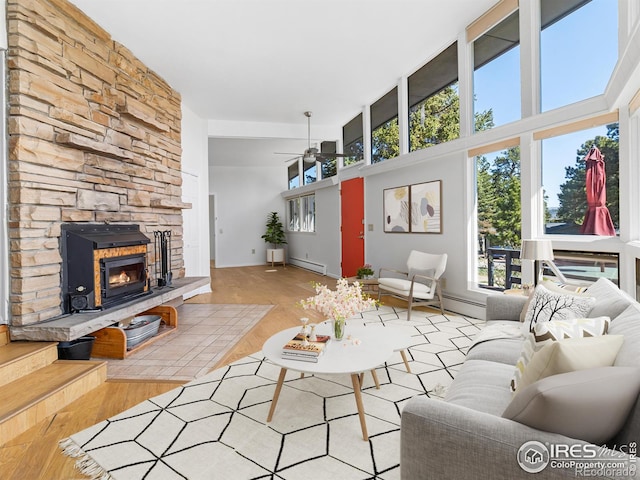 1411 Vail Ct, Estes Park, CO 80517 - living room featuring wood finished floors, ceiling fan, a stone fireplace, baseboard heating, and a towering ceiling