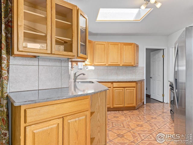 1411 Vail Ct, Estes Park, CO 80517 - kitchen featuring a sink, a skylight, freestanding refrigerator, decorative backsplash, and glass insert cabinets