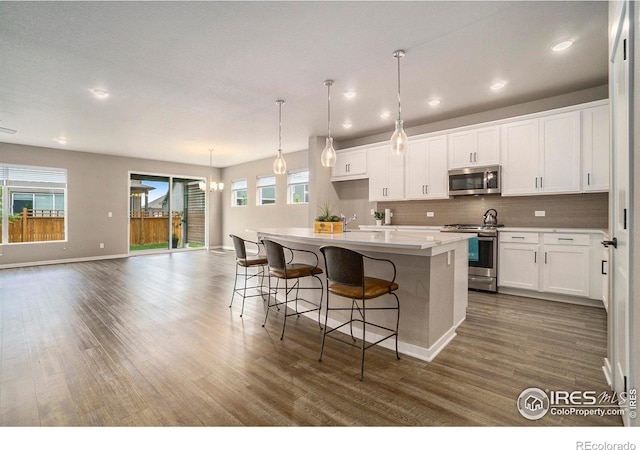 kitchen with dark wood finished floors, white cabinetry, a kitchen island, and appliances with stainless steel finishes