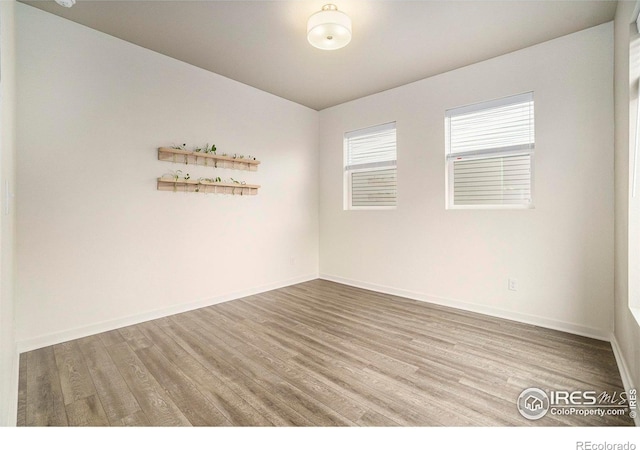 spare room with baseboards and wood finished floors
