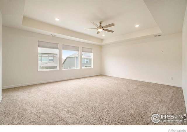 empty room with a tray ceiling, carpet floors, a ceiling fan, and recessed lighting