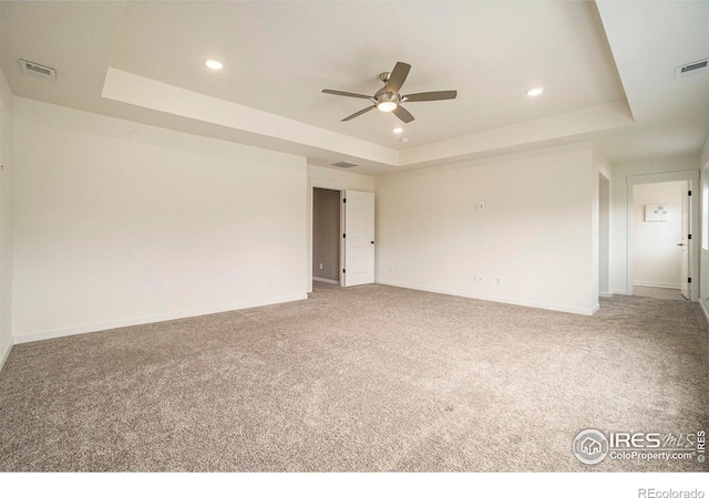 carpeted spare room featuring a ceiling fan, visible vents, a raised ceiling, and recessed lighting
