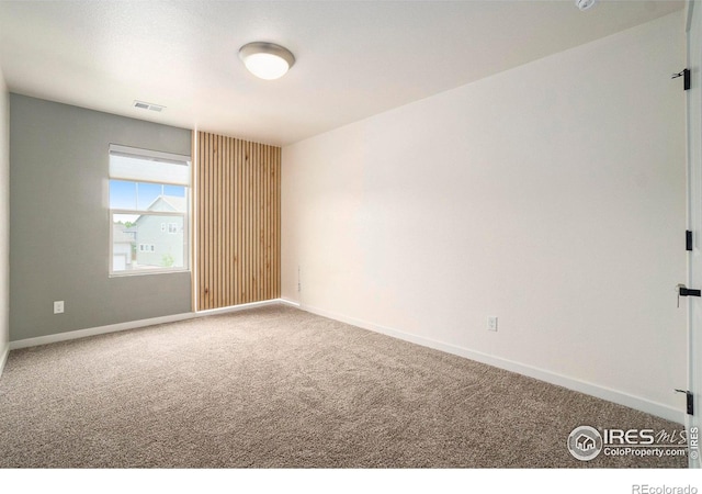carpeted spare room featuring baseboards and visible vents