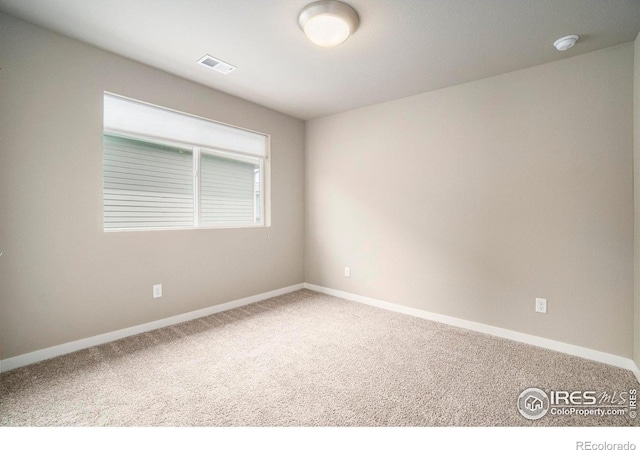carpeted spare room featuring baseboards and visible vents