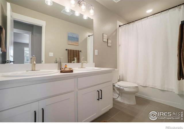 bathroom with toilet, tile patterned flooring, double vanity, and a sink