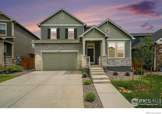 craftsman-style home with fence, a garage, stone siding, and driveway