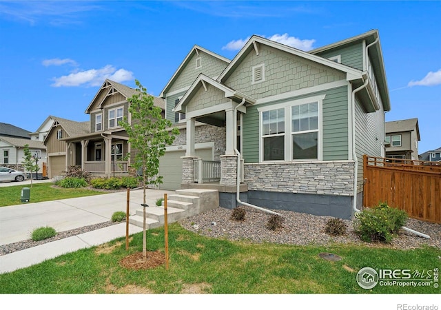 craftsman-style home featuring fence, a garage, concrete driveway, stone siding, and a front lawn