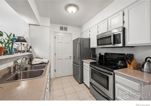 5086 Buckingham Rd, Boulder, CO 80301 - kitchen featuring appliances with stainless steel finishes, a sink, light tile patterned flooring, white cabinets, and light countertops