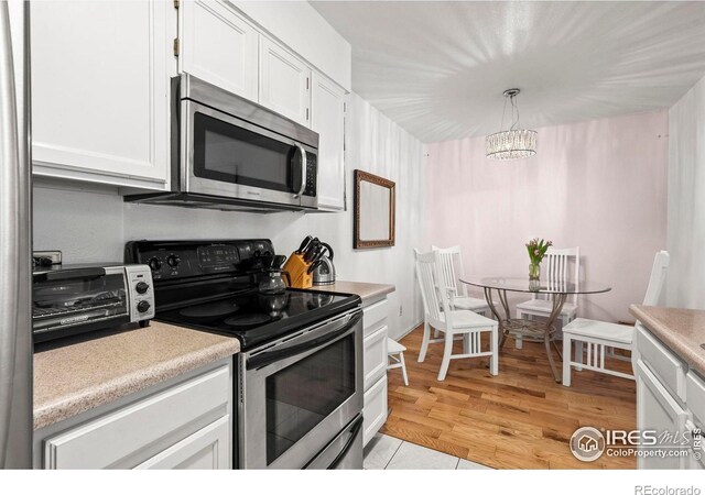 5086 Buckingham Rd, Boulder, CO 80301 - kitchen with appliances with stainless steel finishes, white cabinetry, light countertops, and hanging light fixtures