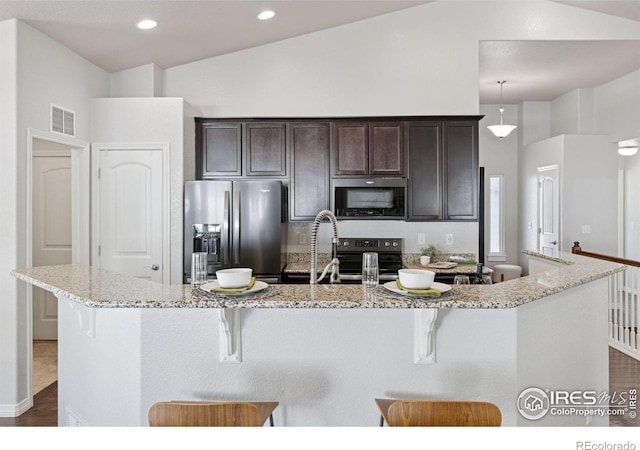 9137 Harlequin Cir, Frederick, CO 80504 - kitchen featuring stainless steel appliances, a breakfast bar area, dark brown cabinets, a center island with sink, and recessed lighting