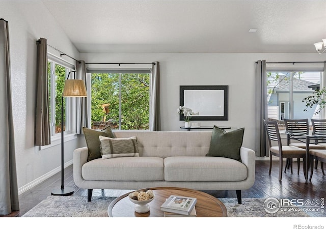 9137 Harlequin Cir, Frederick, CO 80504 - living area with plenty of natural light, baseboards, wood finished floors, vaulted ceiling, and a chandelier