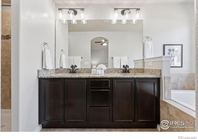 9137 Harlequin Cir, Frederick, CO 80504 - bathroom featuring ceiling fan, double vanity, and a relaxing tiled tub