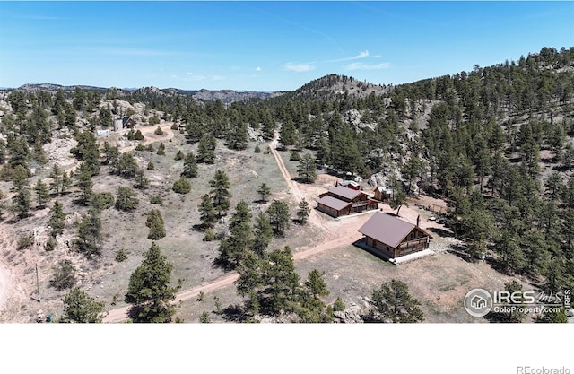 view of subject property featuring a heavily wooded area and a mountain backdrop