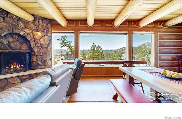 interior space with log walls, wooden ceiling, beamed ceiling, and a stone fireplace