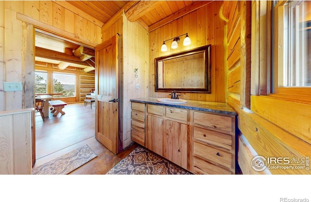 bathroom featuring wood ceiling, wooden walls, beam ceiling, and vanity