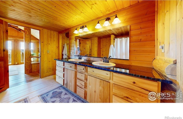 bathroom featuring wooden walls, plenty of natural light, hardwood / wood-style floors, wood ceiling, and double vanity