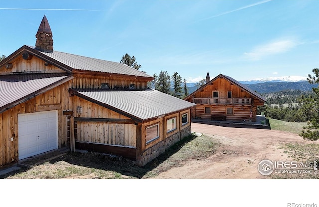 view of property exterior with a chimney, a mountain view, metal roof, and an outdoor structure