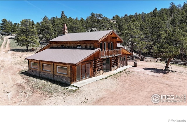 view of front of property with stone siding, french doors, fence, and metal roof