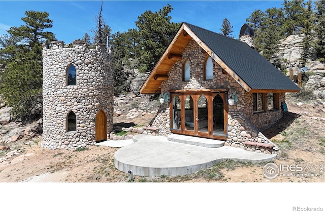 view of front of property featuring stone siding, french doors, and a chimney