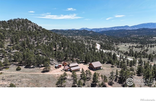 aerial view of property and surrounding area with mountains and a heavily wooded area
