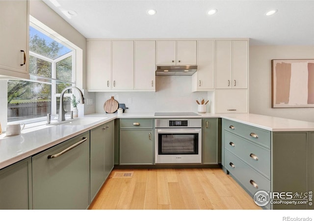 536 W Sycamore Cir, Louisville, CO 80027 - kitchen featuring stainless steel oven, a sink, light wood-type flooring, black electric stovetop, and under cabinet range hood