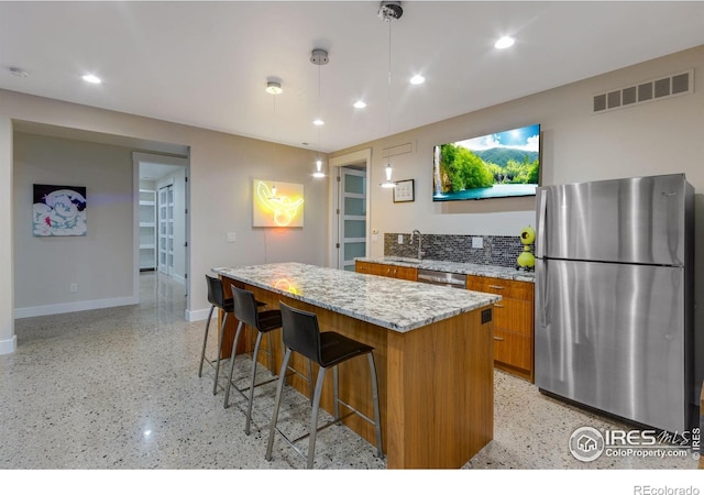 9360 Gold Mine Rd, Loveland, CO 80538 - kitchen with stainless steel appliances, brown cabinetry, a kitchen island, baseboards, and dark speckled floor
