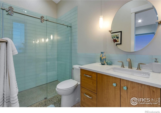 9360 Gold Mine Rd, Loveland, CO 80538 - bathroom with tiled shower, tile walls, toilet, vanity, and a wainscoted wall