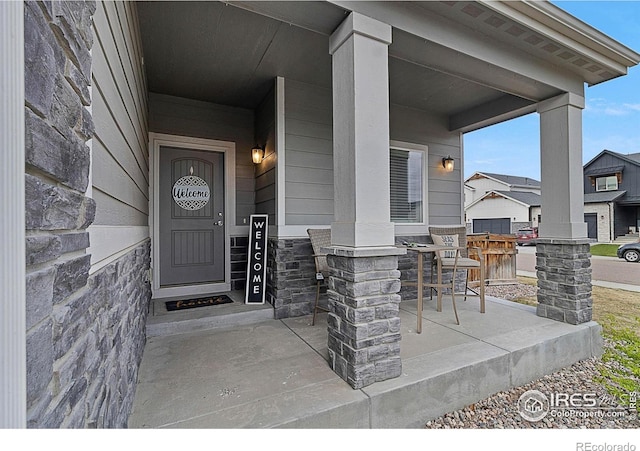 view of exterior entry with a porch and stone siding