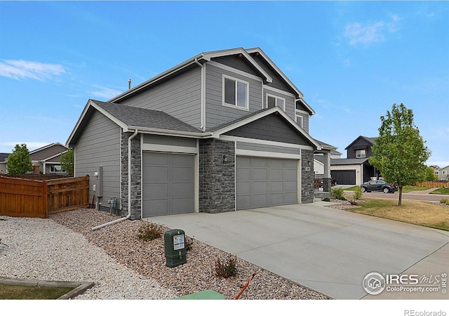 craftsman inspired home featuring fence, stone siding, concrete driveway, and an attached garage