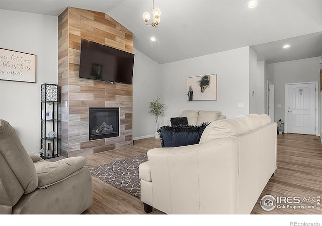 living room with a tiled fireplace, vaulted ceiling, wood finished floors, recessed lighting, and a chandelier