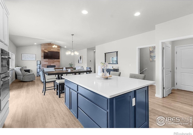 kitchen featuring blue cabinets, light wood finished floors, open floor plan, light countertops, and a kitchen island