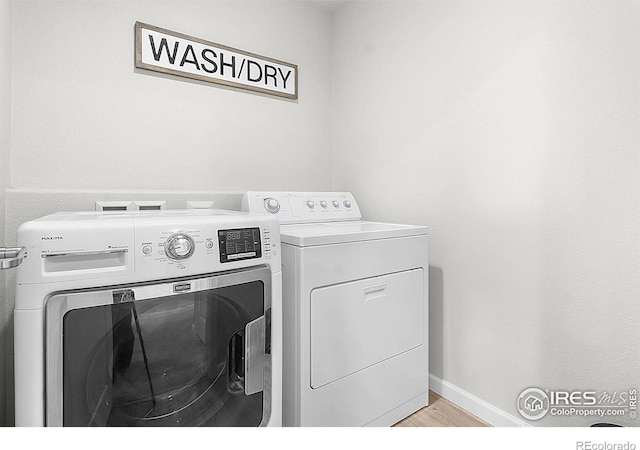 washroom featuring separate washer and dryer, light wood-style flooring, and baseboards