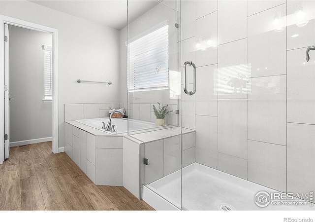 full bathroom featuring wood finished floors, a stall shower, and a bath