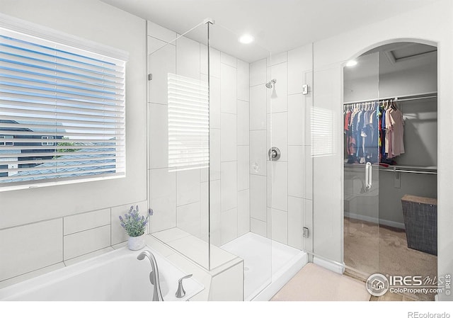 full bath featuring a shower stall, a bath, and a spacious closet