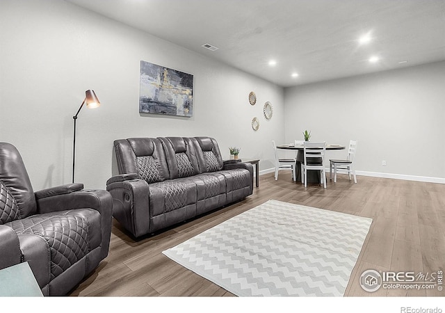 living room featuring light wood-type flooring, recessed lighting, and baseboards
