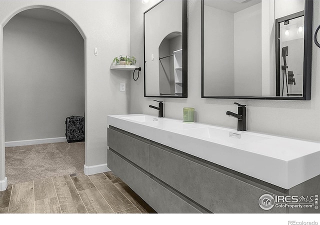 full bathroom featuring wood finished floors, double vanity, and baseboards