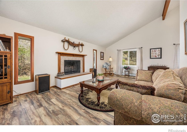 living room featuring wood finished floors, a fireplace, high vaulted ceiling, baseboards, and beam ceiling