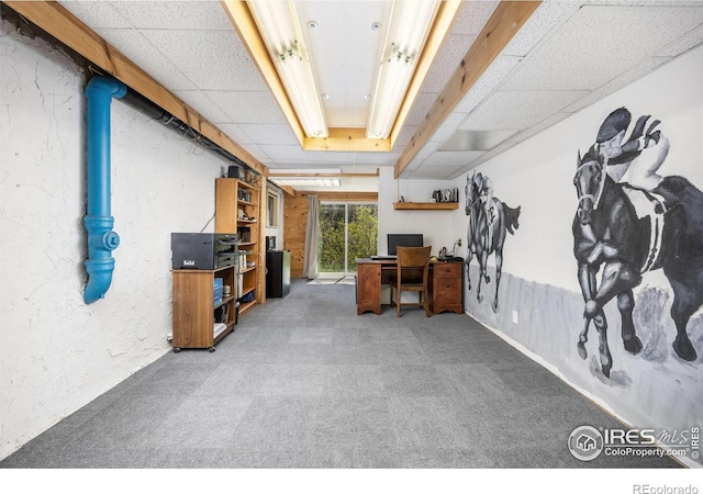 below grade area with carpet flooring, an office area, and a paneled ceiling