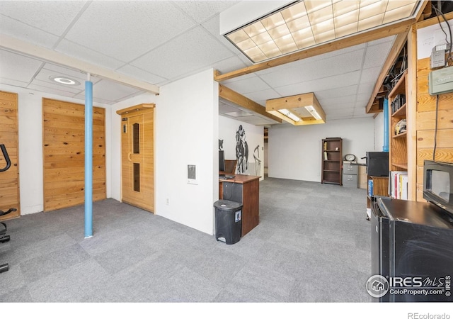 finished below grade area with a paneled ceiling and carpet flooring