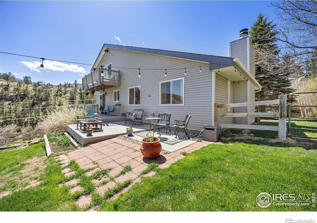 rear view of property with a wooden deck, a chimney, a balcony, and a patio area
