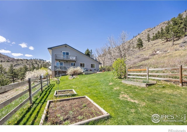 view of yard featuring a garden, a mountain view, and a balcony