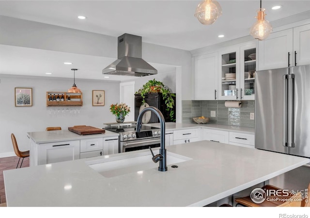 kitchen featuring stainless steel appliances, wall chimney exhaust hood, a kitchen bar, white cabinets, and light countertops