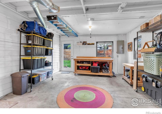 recreation room featuring electric panel, a workshop area, and concrete floors