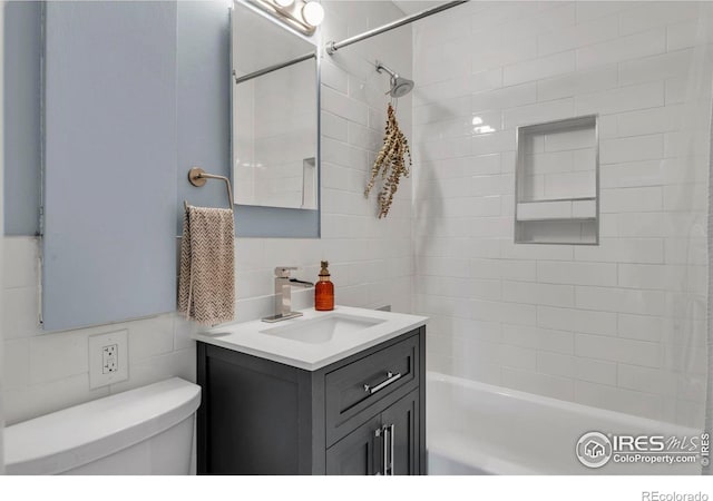 bathroom featuring tile walls, vanity, toilet, decorative backsplash, and shower / bath combination