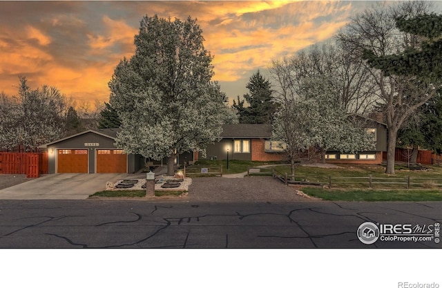 view of front of house featuring fence, driveway, and an attached garage