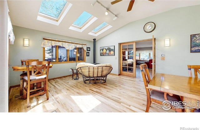 bedroom featuring rail lighting, vaulted ceiling, a skylight, wood finished floors, and baseboards